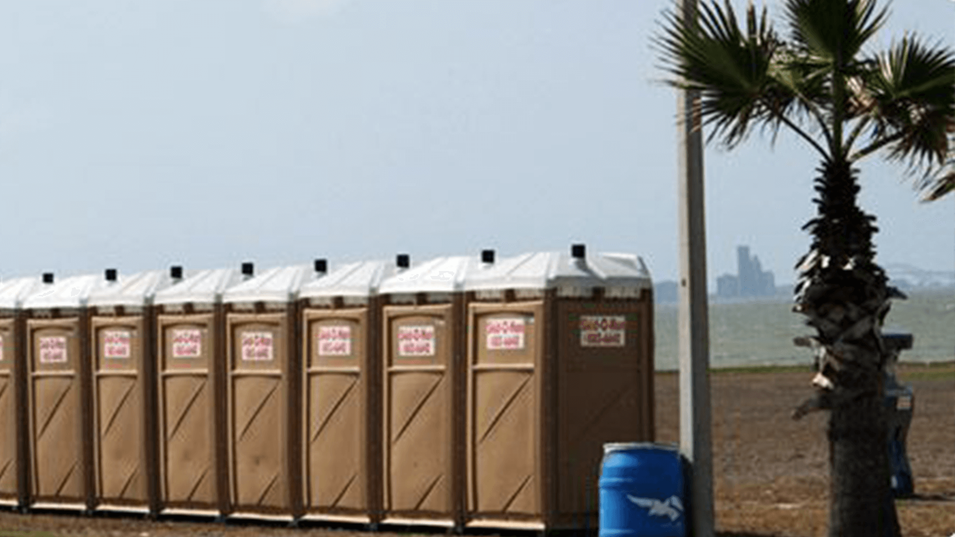 Skid o Kan portable toilets in South Texas by a palm tree.