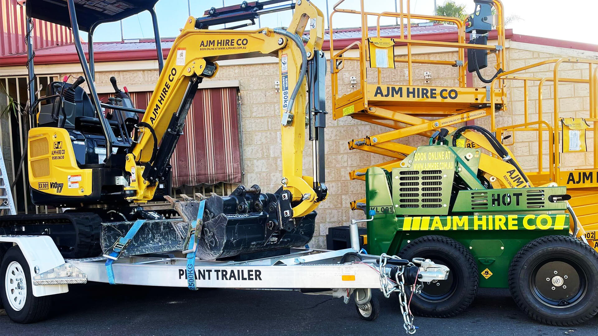 An AJM mini-excavator on a trailer with a scissor lift