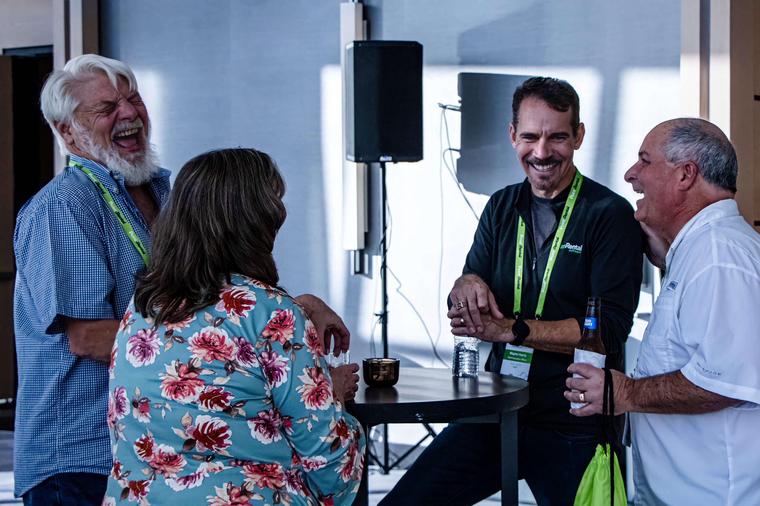 Point of Rental CEO Wayne Harris and several 2022 International Conference attendees laugh around a table.