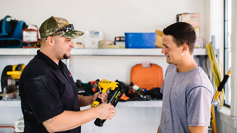 A rental employee works with a customer at a general tool counter.