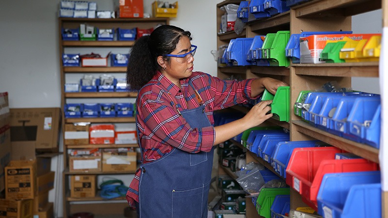 A woman checks parts inventory on shelving. 