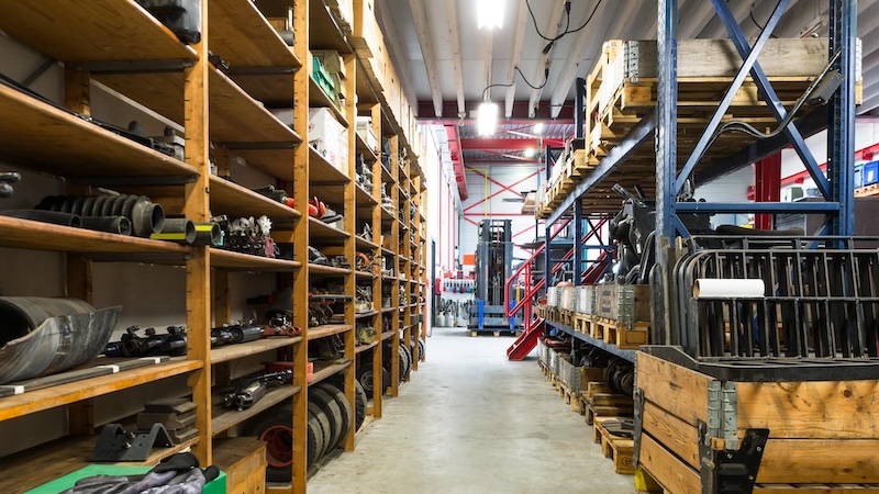 A clean hallway with parts stored neatly on yellow metal shelves.