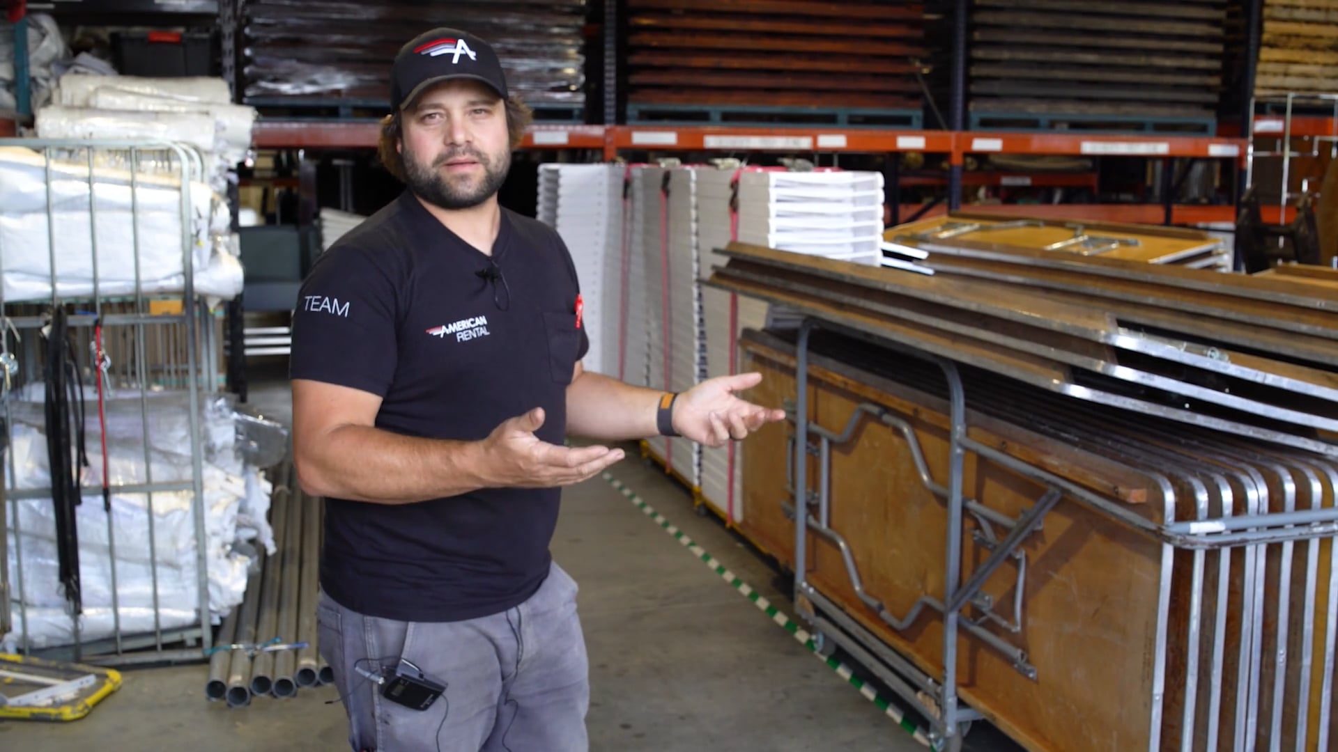 Brad Kniep in the American Rental warehouse stands next to a stack of tables that are pre-staged to go on the next truck.