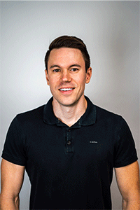 Portrait of a smiling man in a black polo shirt against a light gray background.